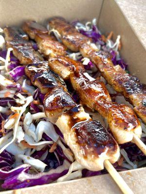 Teriyaki chicken and pineapple skewers on a salad salad