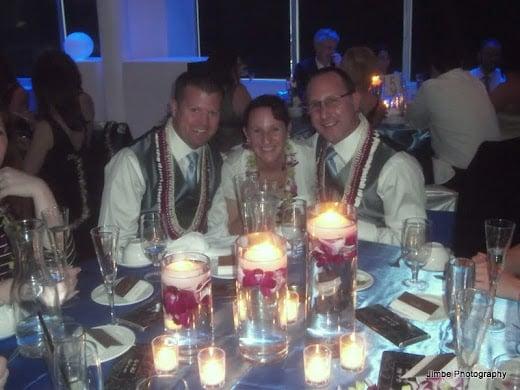 Grooms Lee and Rob at table with a friend at the wedding reception.