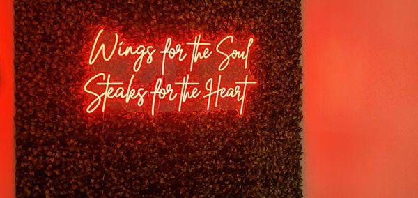 ("Wings for the Soul
 Steaks for the Heart"
 red neon sign set into fake hedge backing)