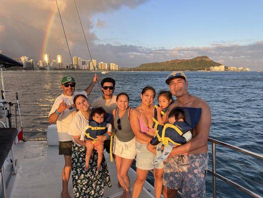 Family on a boat near Waikiki and Diamond Head Mountain with a rainbow in the background.