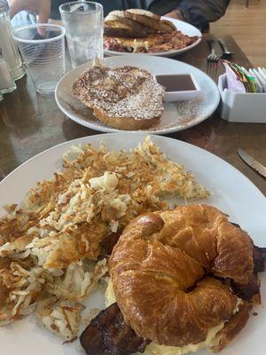 Cornish Quickie with bacon and gouda on croissant and hash browns as the side. Gypsy toast to share! Cornish had with eggs in the back.