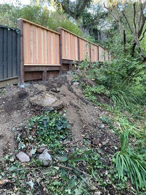 Red wood fence with retaining wall.