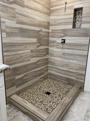 Plank tile shower with schluter edging and mosaic basin and niche.