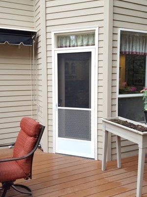 Swinging screen door with a pet grill and kick panel