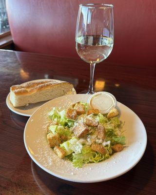 side Caesar salad, garlic bread, glass of Sauvignon Blanc