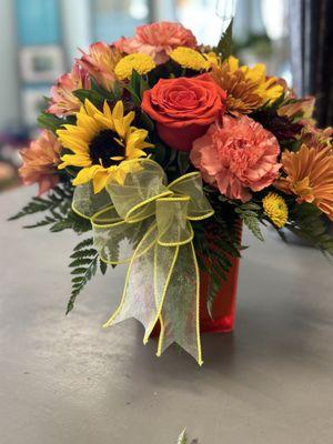 Beautiful Fall Arrangement, in a amber glass vase . Sunflowers, peach, orange yellow  assorted flowers ..