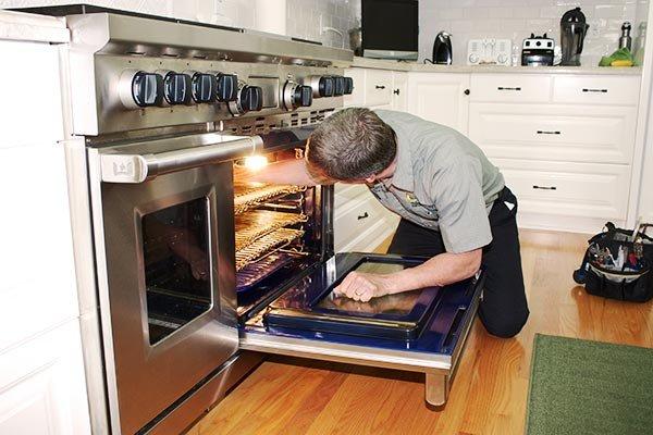 Professional repairman fixing oven.