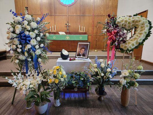 Blue and white standing spray (left), white standing heart with red rose (right), white roses and blue forget-me-nots (foreground)