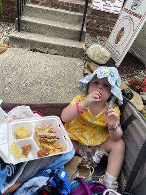 The baby eating leftover chicken fingers, fries, and her brothers cheeseburger!