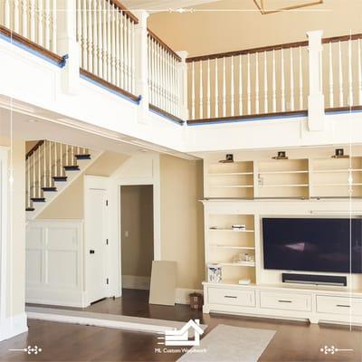 tv built-in and stairs balcony between wood paneling