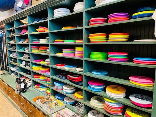 Sunflower has a wall of shelves loaded with discs and bags for disc golf and Ultimate players.