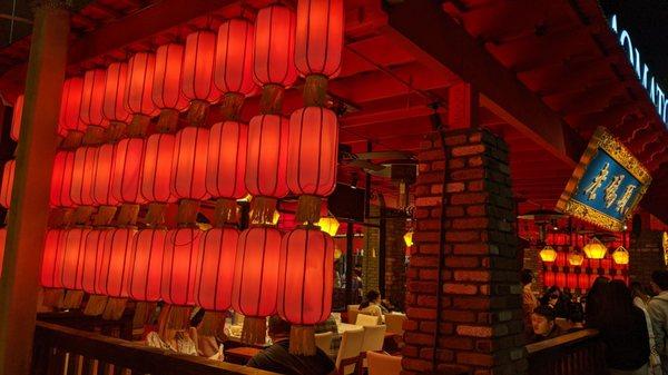 A wall of traditional red lanterns on one side of the outdoor dining area