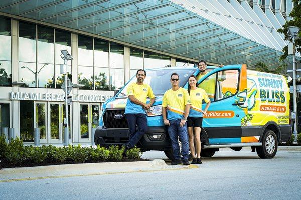 Sunny Bliss Plumbing & Air team with van in front of landmark Miami Beach convention center.