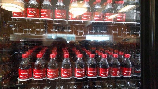 The workers have stocked the Coke case to make it easy to find names.