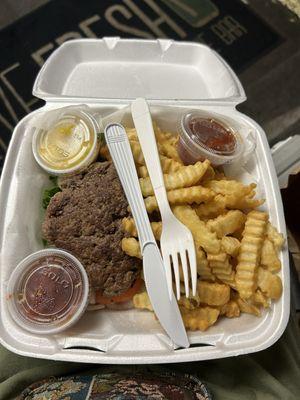 Burger on a bed of lettuce, onion, tomato, & pickle with french fries