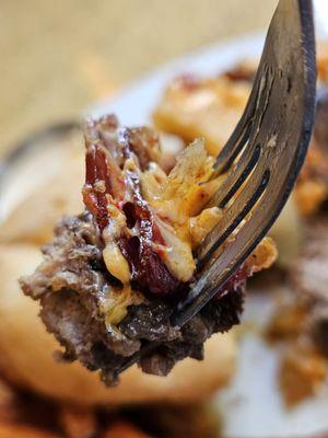 Close-up of a fork holding a piece of the burger and all of the ingredients from inside.