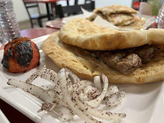 Beef and lamb koobideh kebab inside a huge naan. Toasted tomato. Sliced onions.