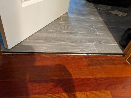 Tile to wood floor transition with underlay visible.