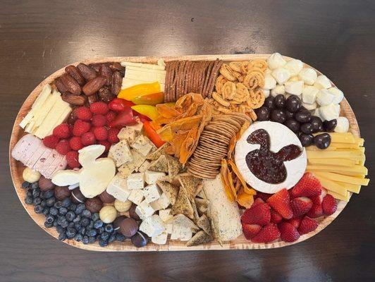 A bunny themed board featuring various cheeses, dried fruits, crackers, chocolates, and fresh fruit.