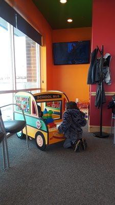 Movie playing in clean main lobby with interactive games, coat rack & comfortable seating!