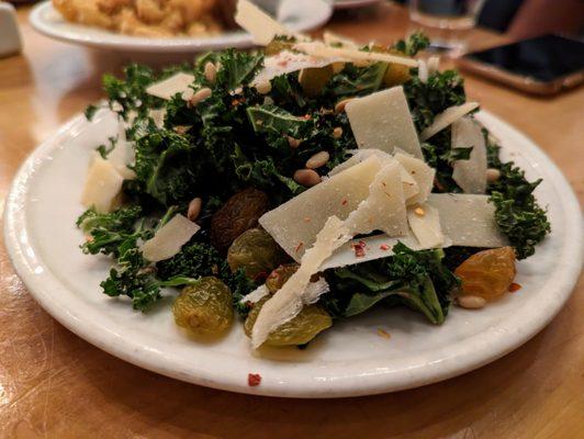 Kale Salad. Large $10. Pictured here is 1/2 serving. Pine nuts, golden raisins, shaved Parmesan, chili flakes, citrus vinaigrette.