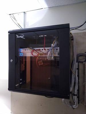 Locking wall cabinet with modem and managed network firewall, switches, and backup battery for a small office network.