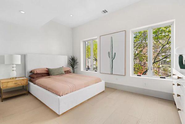 Primary bedroom with large windows. Fresh paint and lighting.