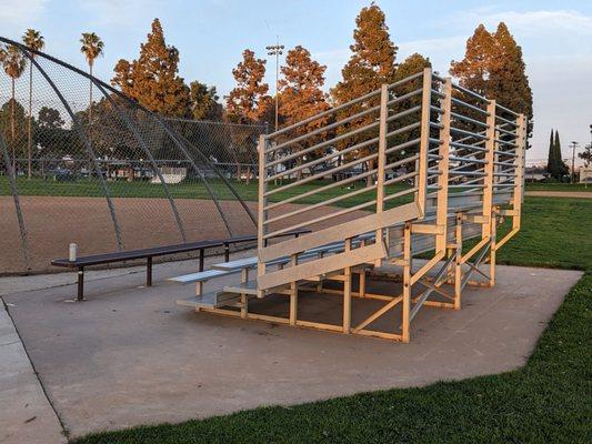 Bleachers and bench by the softball/kickball field. I wonder who left their water bottle there?