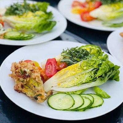 Breaded Zucchini Flower Stuffed with herb cheese on top of a salad.