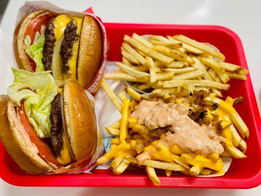 A double and a single cheeseburger, one with animal style fries.