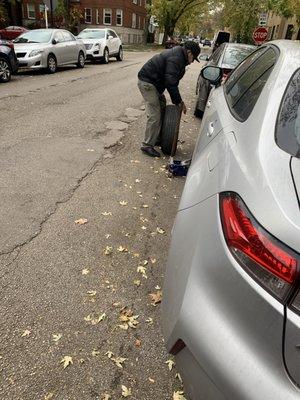 Raul working hard to install a tire onto my car so that it can be towed