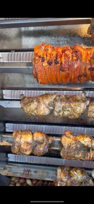 His huge rotisserie , cooking porchetta and roast chicken.