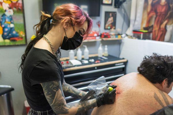 Samm working on a back tattoo in her station