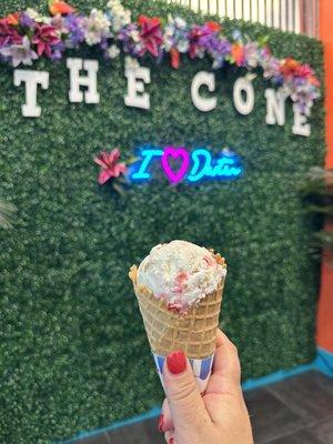 Strawberry cheesecake ice cream in a waffle cone