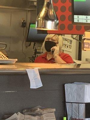 Manager standing over the grill without her hair properly pulled back or covered