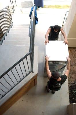 Bird's eye view of Rick and Lorenzo moving a front loading washer on a flat.