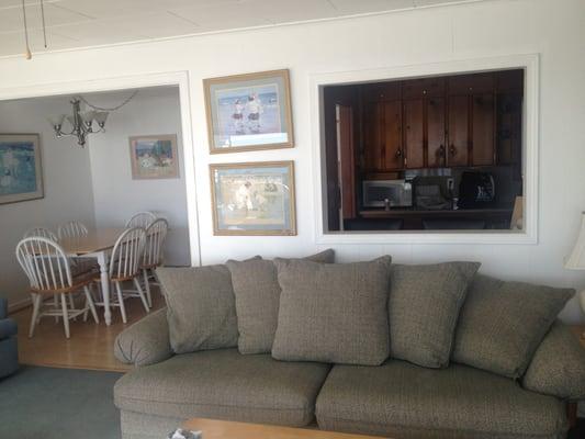 Clean and spacious living room and dining room with window into the kitchen.