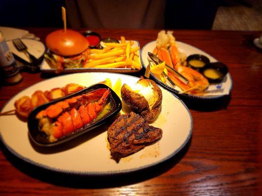 Filet mignon, bacon wrapped scallops, lobster tail,  snow crab legs, baked potato, bacon wagyu burger, French fries.