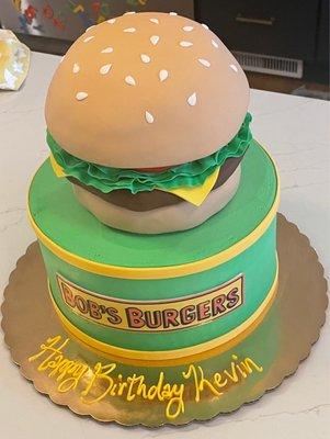 Bob's Burger's themed custom cake with fondant sculpture cheeseburger on top.