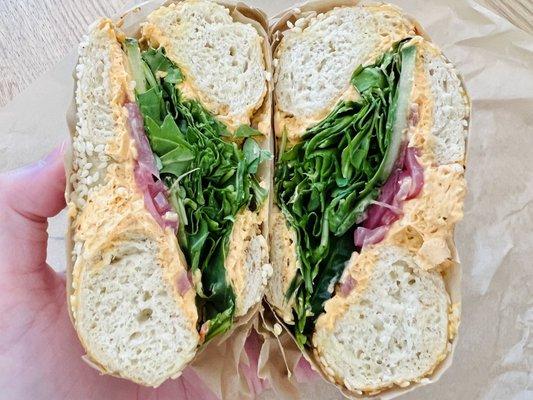 The Grand Central Pete on a sesame bagel (harissa cream cheese, cucumber, arugula, pickled red onion)