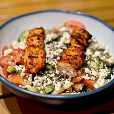 Greek salad with grilled chicken skewers.