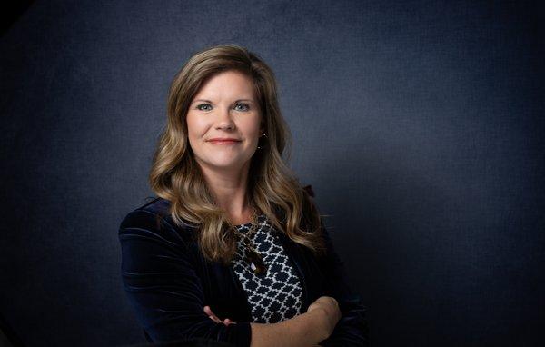 Professional studio headshot, dark blue background