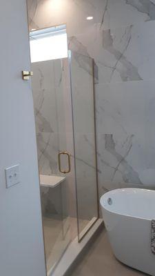 Custom Shower Door and Panel installed with Gold Hardware