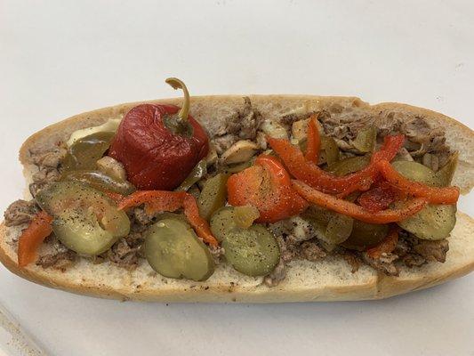 Cheesesteak with hot peppers, sweet peppers, and pickles.