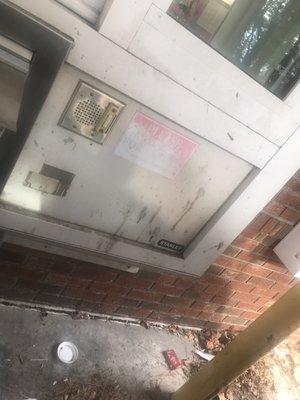 Grimy dirt, trash on the ground and faded labels on outside of pharmacy window.