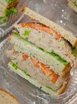 Tuna sandwich served on multigrain bread with lettuce, tomato, onions, arugula