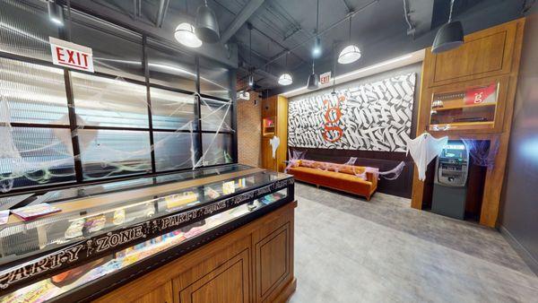 A retail space with a wooden floor, exposed brick walls on the left, and a black metal and glass partition on the right.