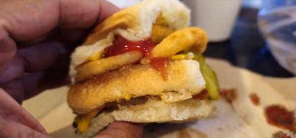 Double cheeseburger with cheese stacked with onion rings on top