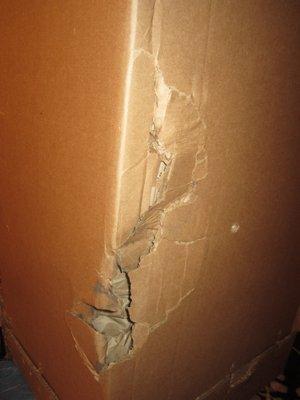 Huge holes/crushing  in cardboard box containing 200 lb column piece, NAVIS packing's cardboard box upon delivery!