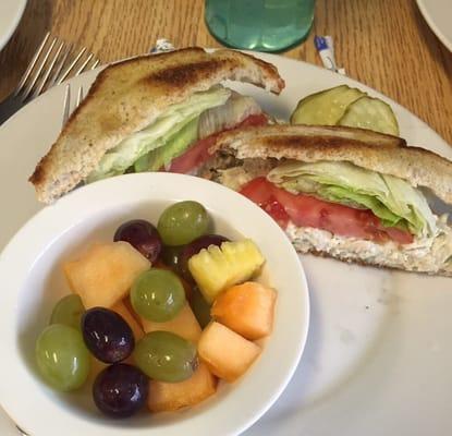 chicken salad sandwich toasted and paired with fresh fruit.